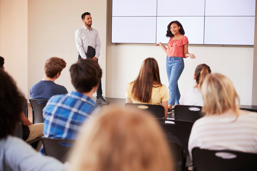 Female Student Giving Presentation to High School Class in Front