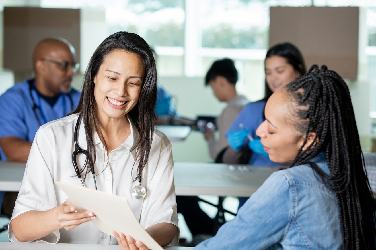 Doctor volunteering at community health fair consults with female patient